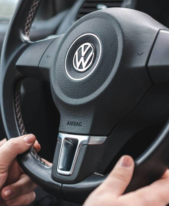 2 hands on a VW steering wheel with the word Airbag visible